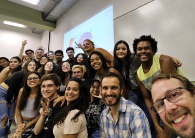 Group of multi-cultural students with two professors in lower corner, with map of South American-type continent projected behind them