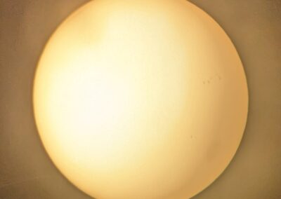 Filtered view of the Sun with a large sunspot in the lower right and a large cluster of sunspots to the upper right of the large sunspot