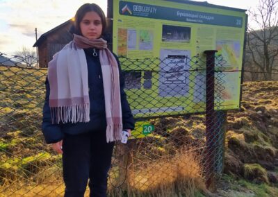 A young woman stands near a descriptive sign that describes the geology of the region